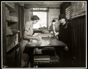 Young woman wrapping up cloth materials for a home worker to take with her, at the New York Association for the Blind, 111 East 59th Street, New York